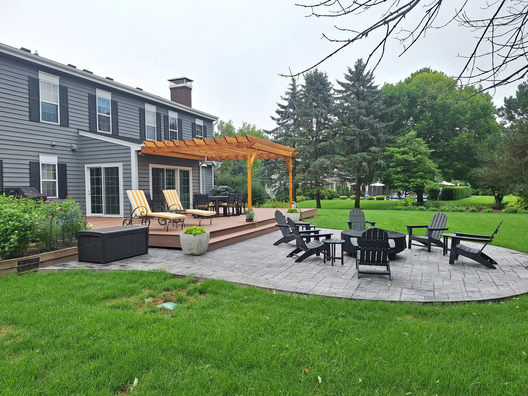 Backyard composite deck with cedar pergola and stamped patio