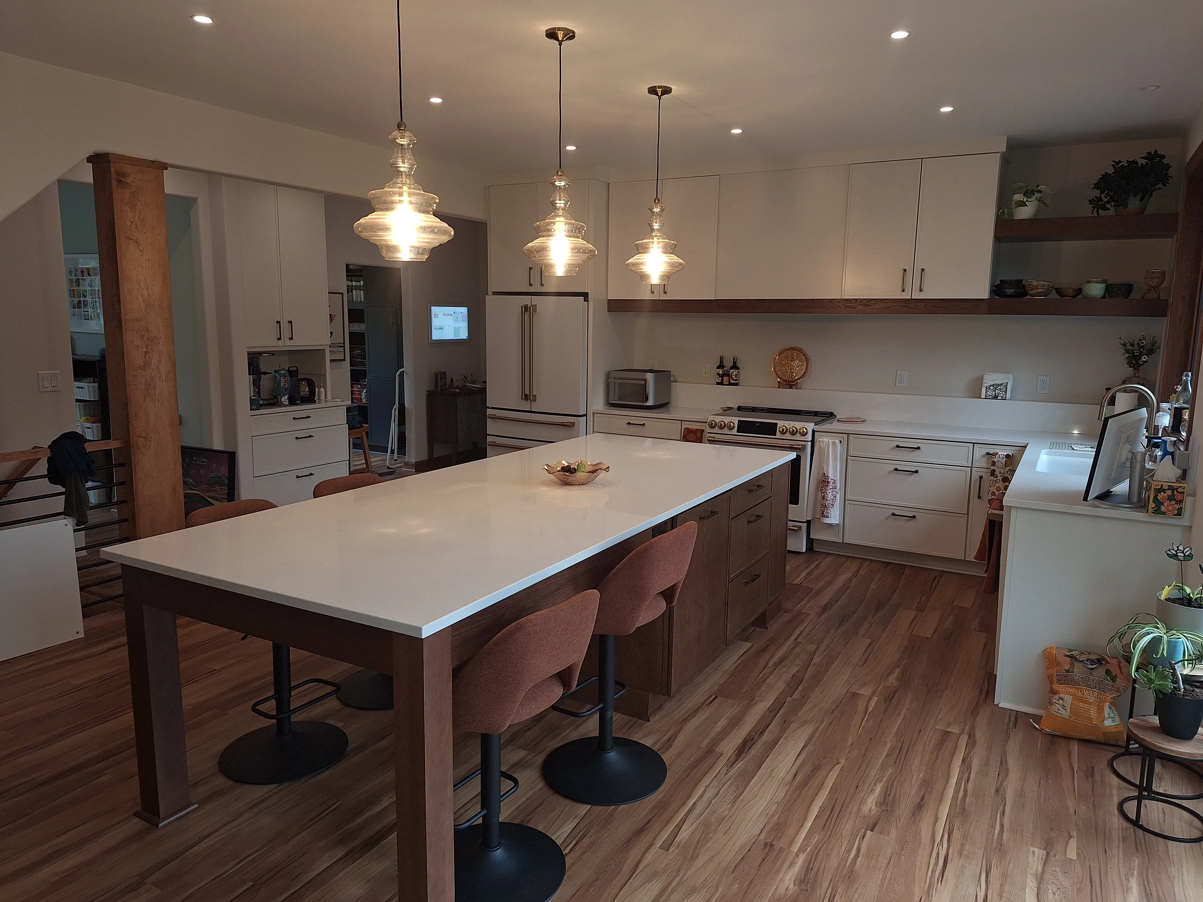 Kitchen remodel with white cabinets, wood accents, and quartz island