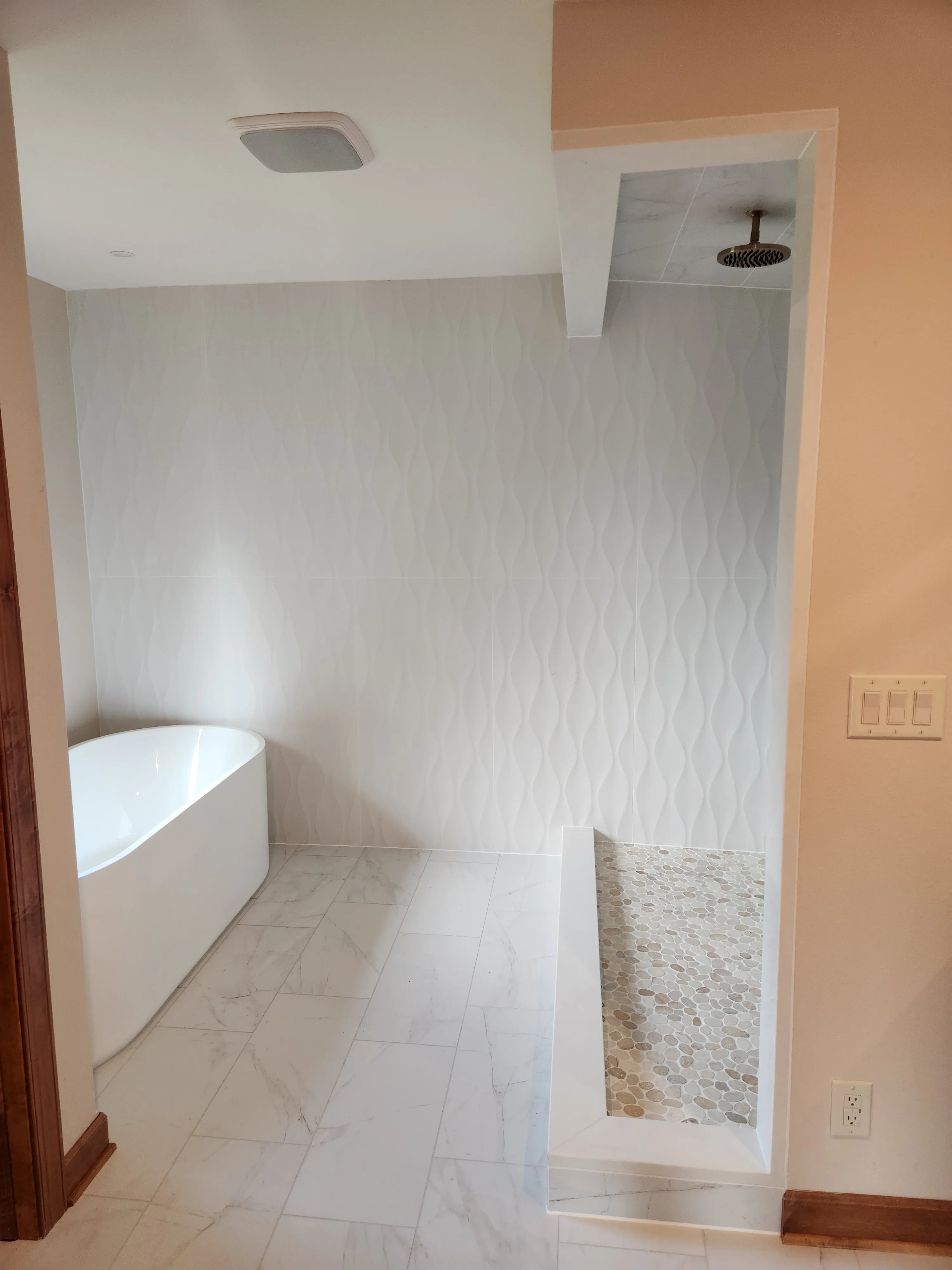 Bathroom renovation with freestanding tub and textured tile wall
